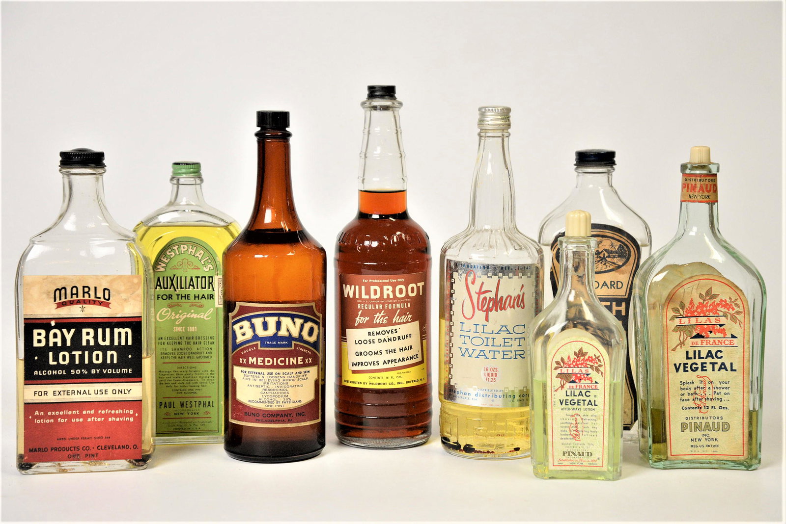 Eight Toilet Water Bottles: All glass with chromolithographed paper labels including Wildroot; Marlo Bay Rum; Stephan’s Lilac Toilet Water Lilas De France Lilac (2); Buno; Standard Witch Hazel; and Westphal’s Auxilia