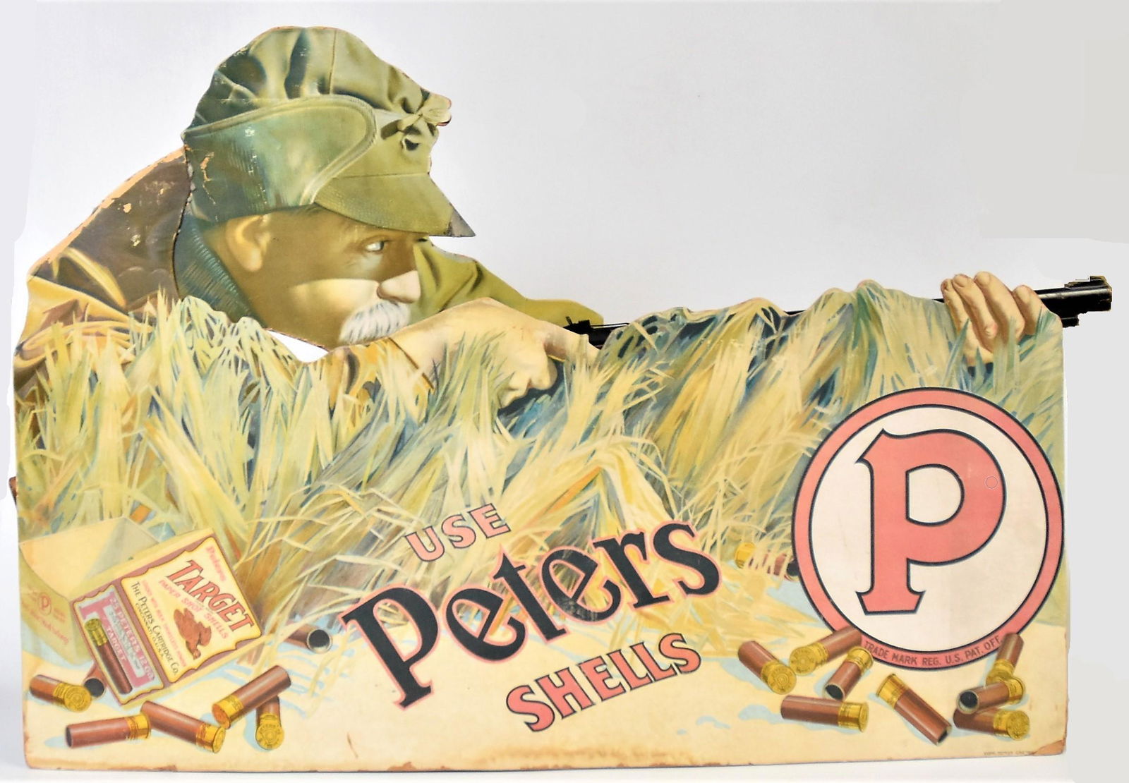 Outstanding Peters Card Stock Display Add: Chromolithographed heavy card stock of hunter in high grass with open box of Target shells at right, he is holding a real Red Rider BB gun with wood stock, 36” long x 23” high with kick stand back