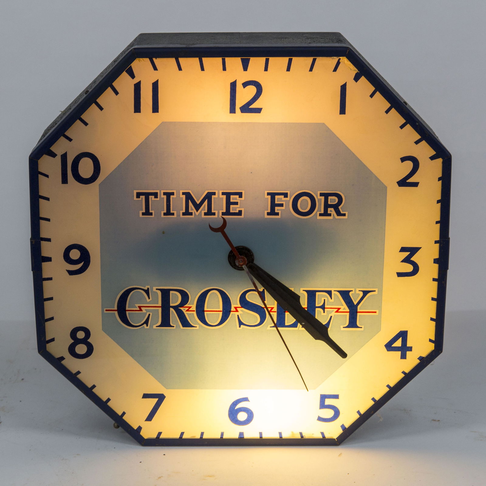 Lighted Crosley Clock: Wall hanging octagonal in blue steel frame with chromolithographed dial with Arabic numerals and text: Time For Crosley, decal on back: Built By Lackner Cin., O.. Electric movement marked Haydon MFG.
