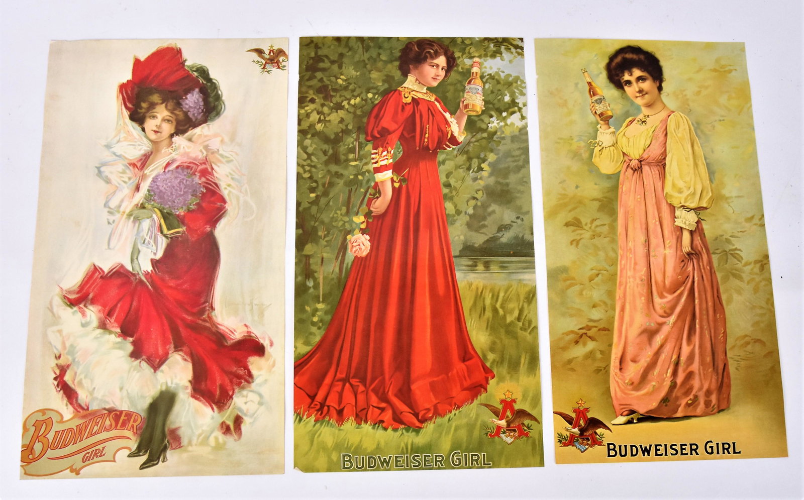 Original Budweiser Girl Chromolithographs: Lot of three all 9 x 17 ¼” with different young ladies in Victorian gowns holding bottle of beer with company logoand Budweiser Girl along lower margin. Trimmed .