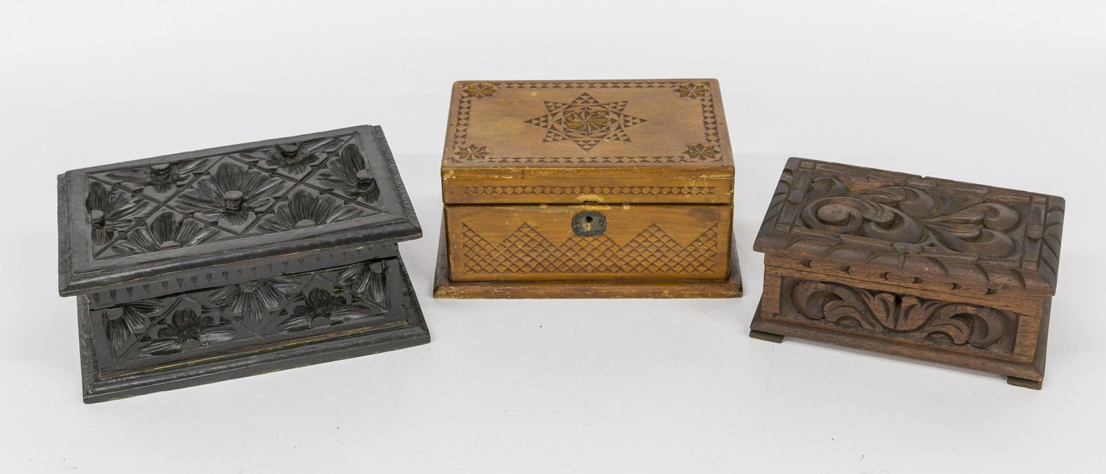 Three Early Carved Boxes: Including one in pine with deep intaglio leaf carved hinged lid and side with cove molding at top and base, in old dark varnish finish, 9 1/2 x 6 1/4 x 4" high; plus second in mahogany with stylized f