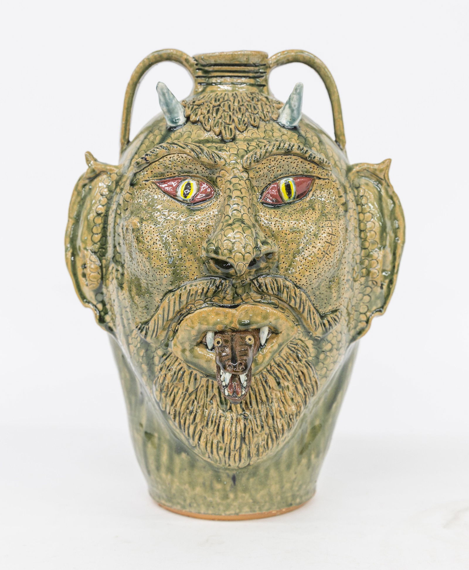 Albert Hodge Face Jug: Polychrome glazed redware horned devil face with snake tongue, inscribed on base Albert Hodge Vale, N.C., with two applied strap handles, 10 1/2" diameter x 14 1/2" high. Condition Fine.