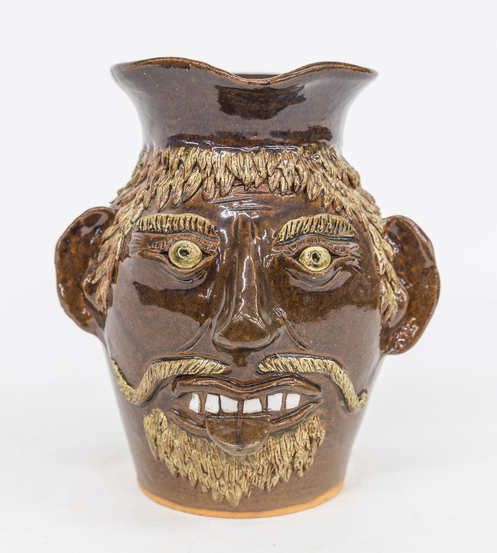 Albert Hodge Face Jug: Albany glazed redware with applied porcelain teeth, white hair and eye, C scroll handle, sgraffito name on base Albert Hodge Newtown, N.C.7 1/2" diameter x 9 1/4" high. Condition Fine.