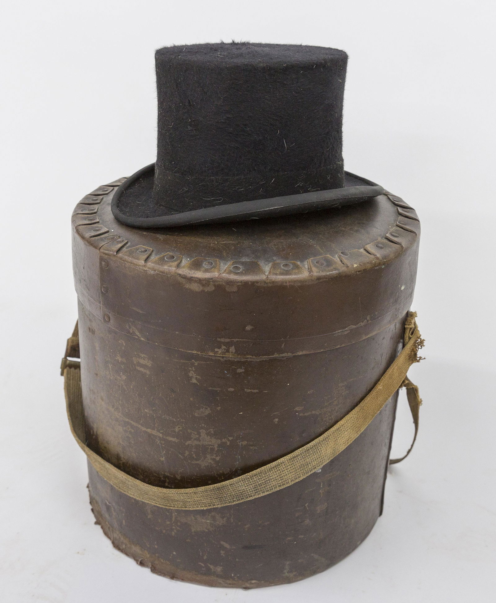 Hat Box & Top Hat: Ladies brown drum form heavy fiber card stock hat box, marked Fibre Case & Novelty Corp. Est. 1894 New York, N.Y., with original woven canvas strap, handle, 15" diameter x 15 1/2" high; and a beaver s