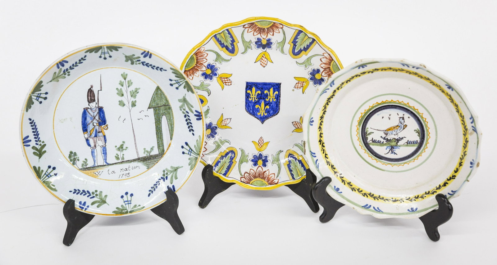 18th Century French Tin Glaze Plates Plus: Lot of three, all tin glazed earthenware, including one with polychrome painted soldier with rifle at guard duty with guard house to right, trees in background inscription below reading: W la nation 1