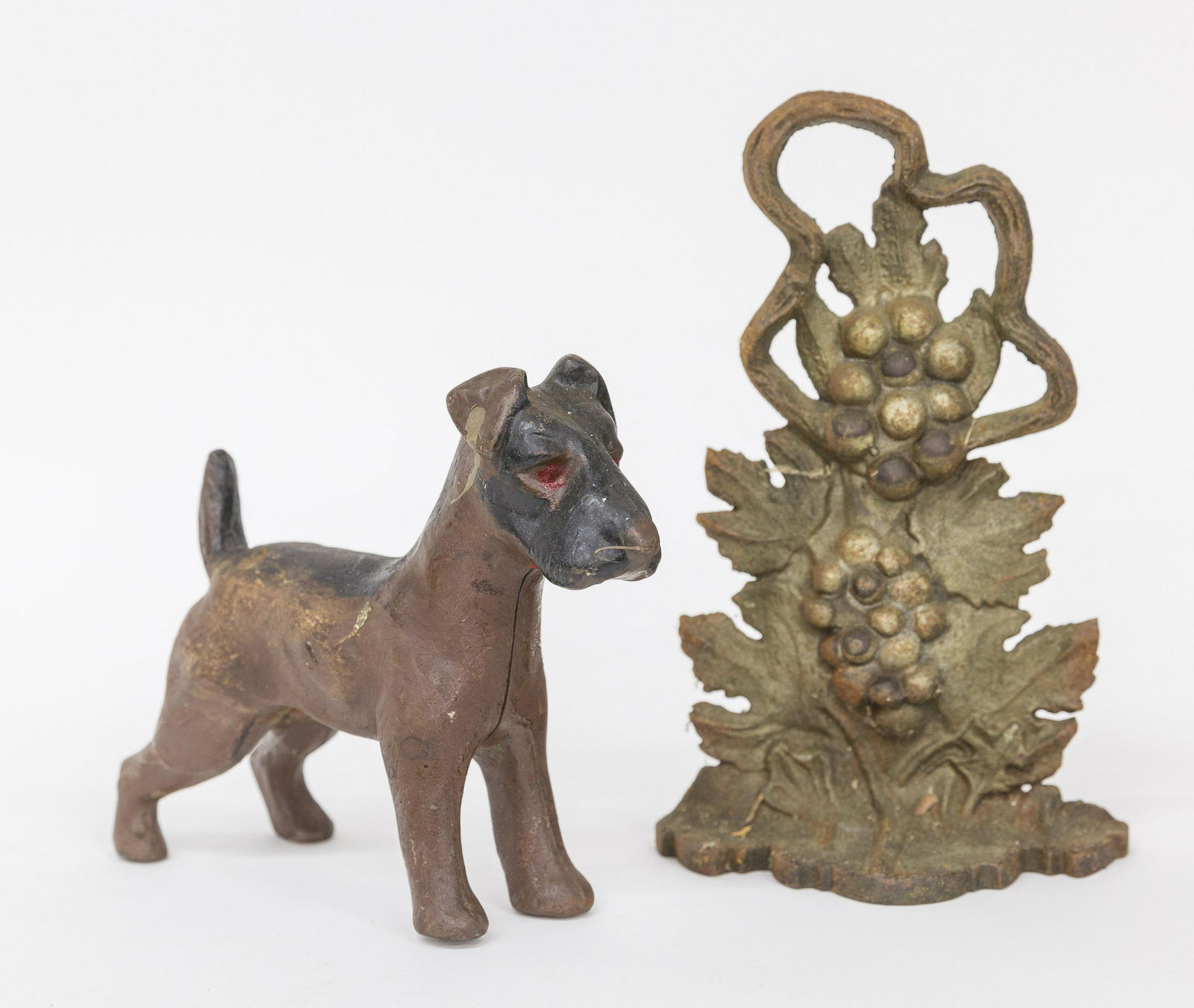 Two Cast Iron Doorstops: Vintage pattern in worn original polychrome painted finish, 6 1/2 x 2 3/4 x 11" high; and standing terrier in old repaint, 9 x 3 x 7 1/2" high. Condition Both VG.