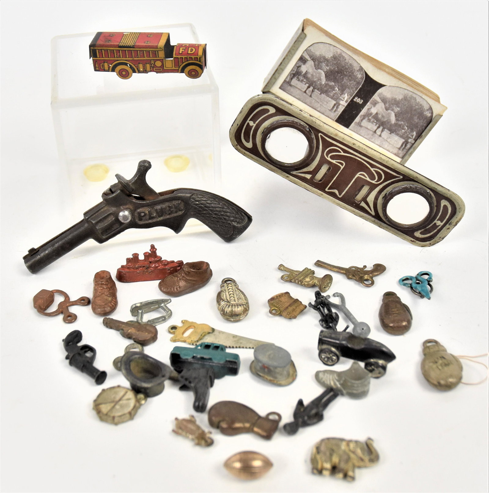 Early Charms & Toys Lot: Lot of 33 pieces including miniature Atkins Silver Seal Saws, 1 1/2" long; plus Plusk cast iron cap gun, 4" long; plus four different boxing gloves; plus four different baby shoes; plus four different