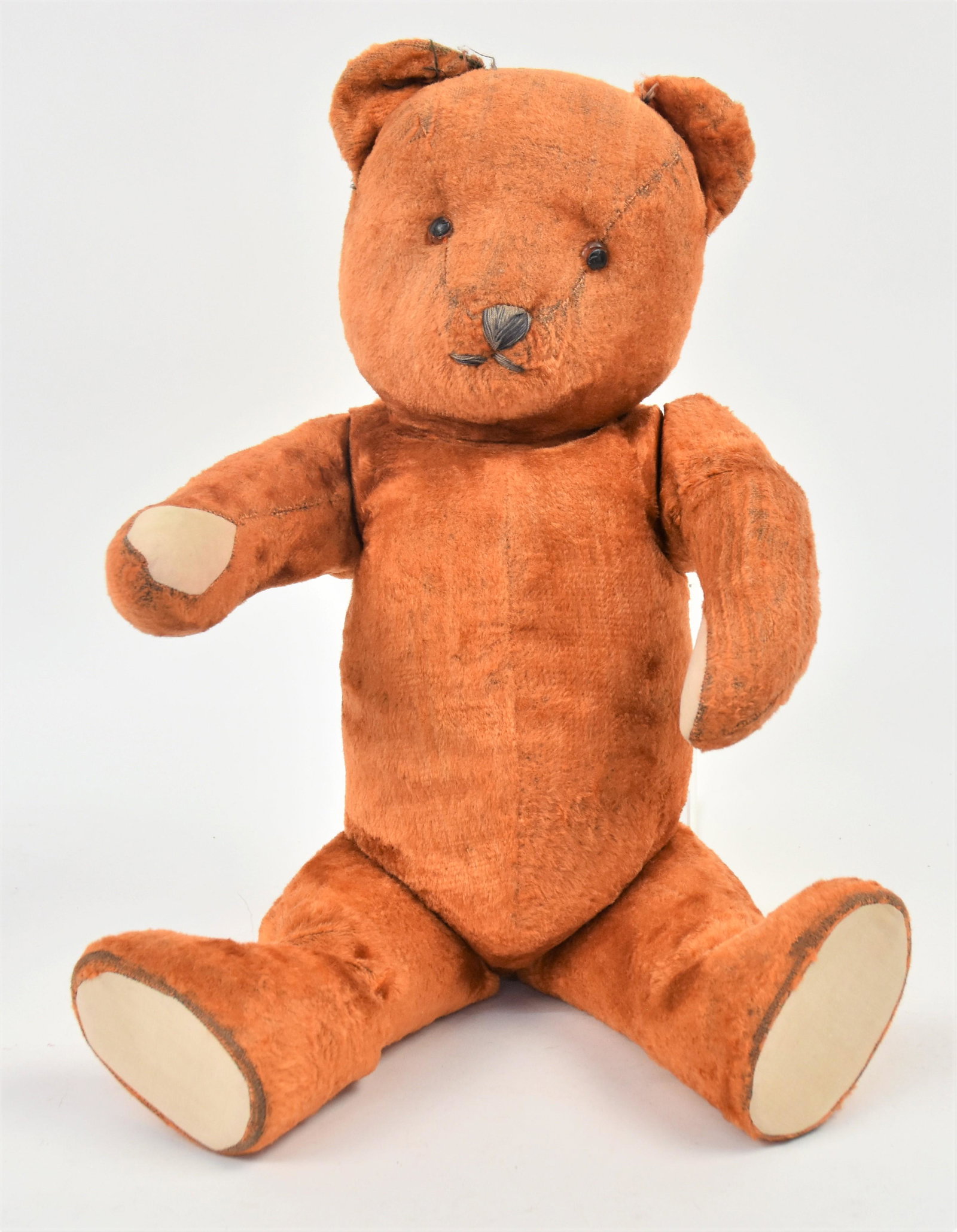 Jointed Cinnamon Teddy Bear: Excelsior stuffed, fully jointed with brown glass eyes, thread sewn mouth and nose, original cream cotton pads on feet, 21" high. Condition minor wear to plush, VG.