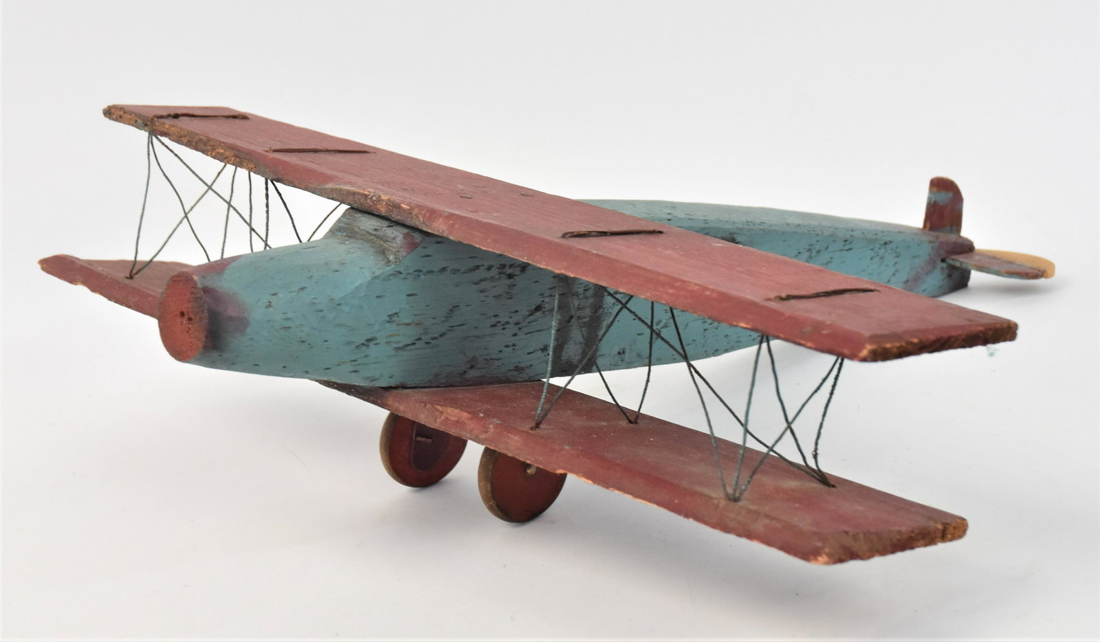 Folk Art Bi-Wing Toy Airplane: In original polychrome painted finish, circa 1930's airliner, 22 x 24 1/2 x 7" high. Condition repair to tail, missing prop and top wing with slight damage.