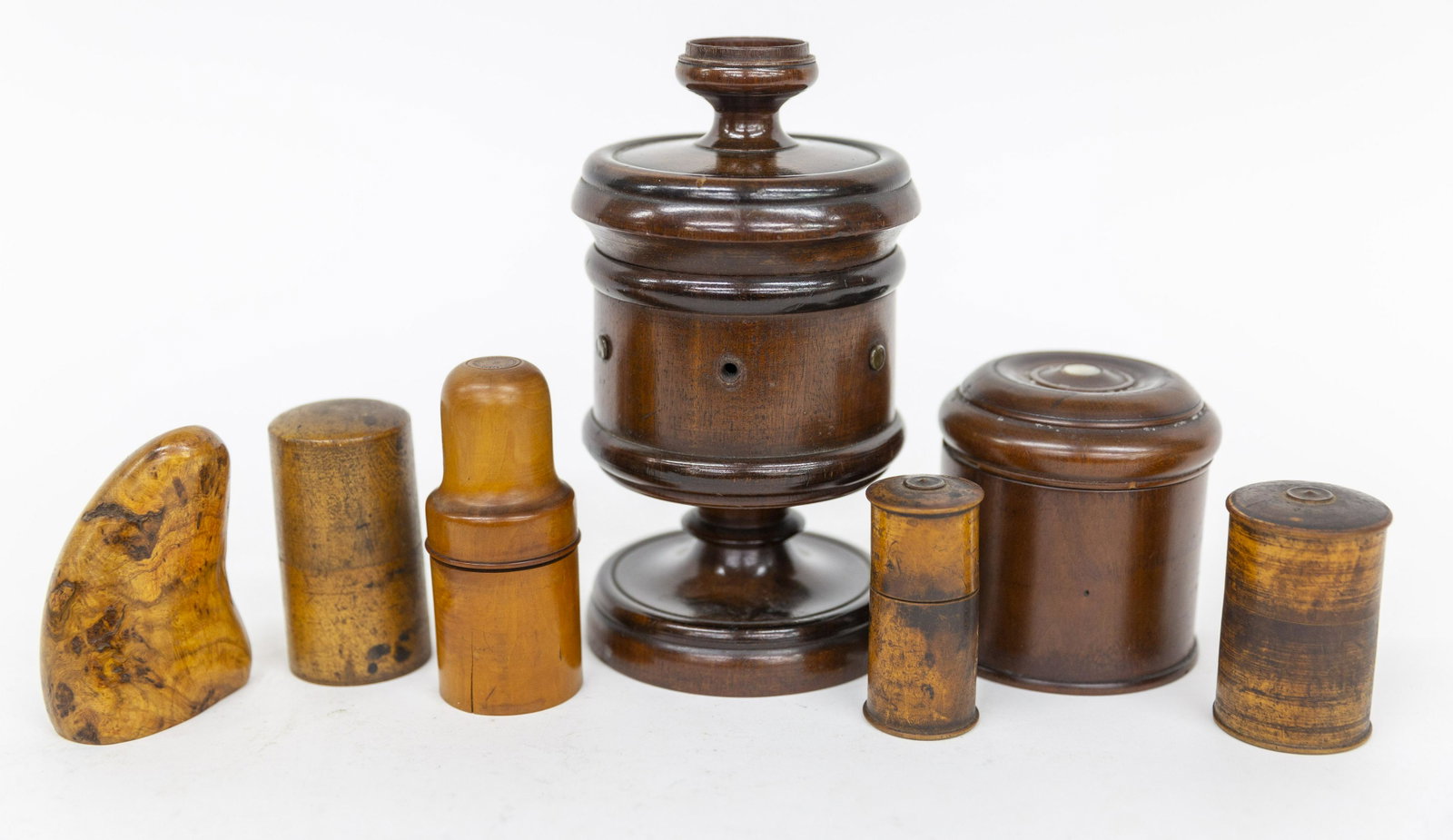 Group of Early Treen: Lot of seven, including a spool thread caddy in mahogany with friction fitted lid with cup finial for pin cushion with six eyelets for thread on pedestal base in original finish, 44 1/4" diameter x 8"