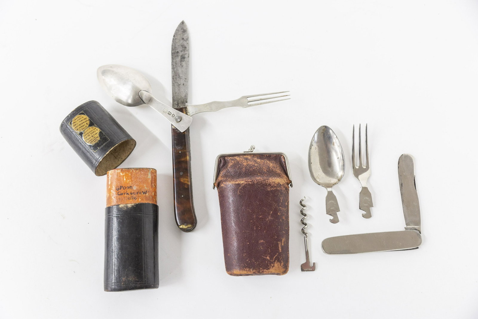 Two Traveling Utensil Kits: Including a British made example in original brown leather case with folding combined knife, fork, spoon & cork screw with horn handled pistol grip form mount, both three tine fork and spoon have Lond