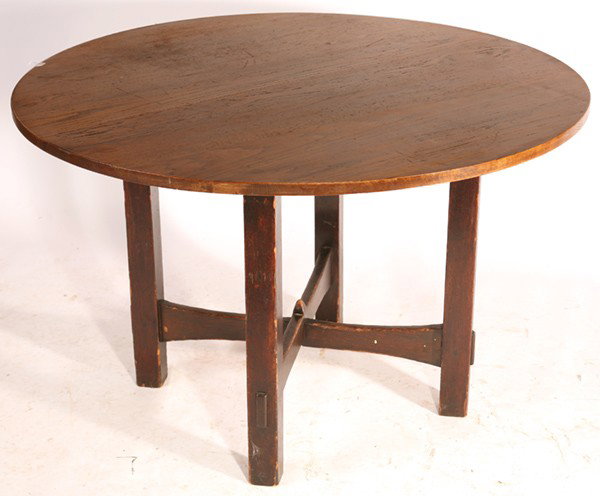 EARLY GUSTAV STICKLEY ROUND TABLE: Scarce form of flared crossed stretchers; thru-tenon construction and pyramid finial. Overhanging replaced top and small loss of height. Original dark finish to base. Unsigned. 28" H x 44" Dia.