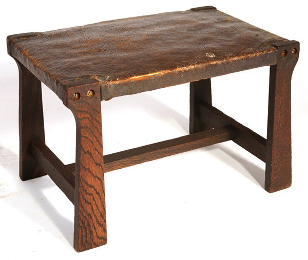 ARTS & CRAFTS (MISSION) FOOTSTOOL: In style of Limbert. Good original finish. Piece of leather missing on one edge of original leather; tacks and wood buttons missing. Fair condition. 12" H x 18 1/2" W x 12" D.