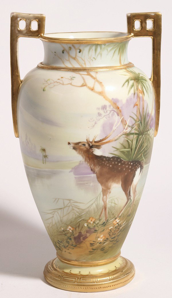 FINE NIPPON VASE W/DEER IN LANDSCAPE: Beautifully handpainted with a stag at the edge of a wooded river, gilt highlights. Marked "Handpainted Nippon" with "M" in wreath. Excellent condition. 12" high.