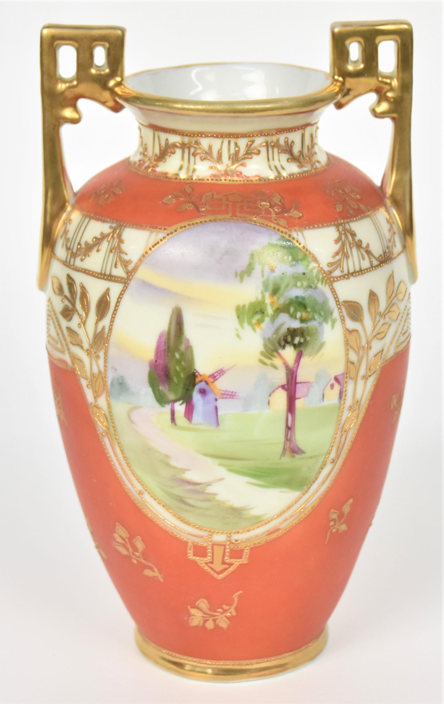 Nippon Pierced Gold Handled Vase: Windmill on front and landscape on reverse. Matte orange with raised gold sprigs and leaves decoration. 7 2/2" tall to handle top. M in wreath backstamp. Good condition.