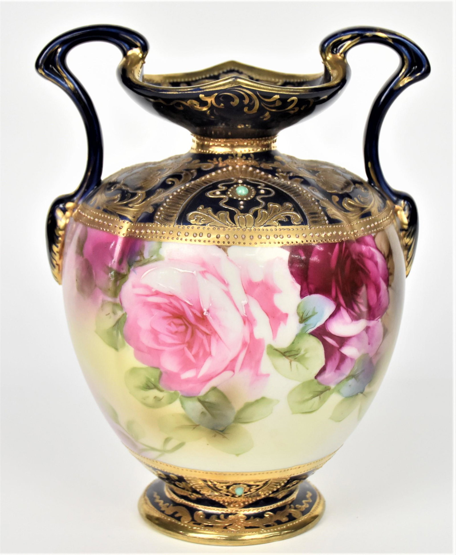 Nippon Cobalt Jeweled Handled Melon Vase: Turquoise beads and lots of ornate gold designs at the top and on base. Old fashion pink and ruby roses at front and back. 8 1/2" tall to top of handles. Faded maple leaf backstamp. Good condition.