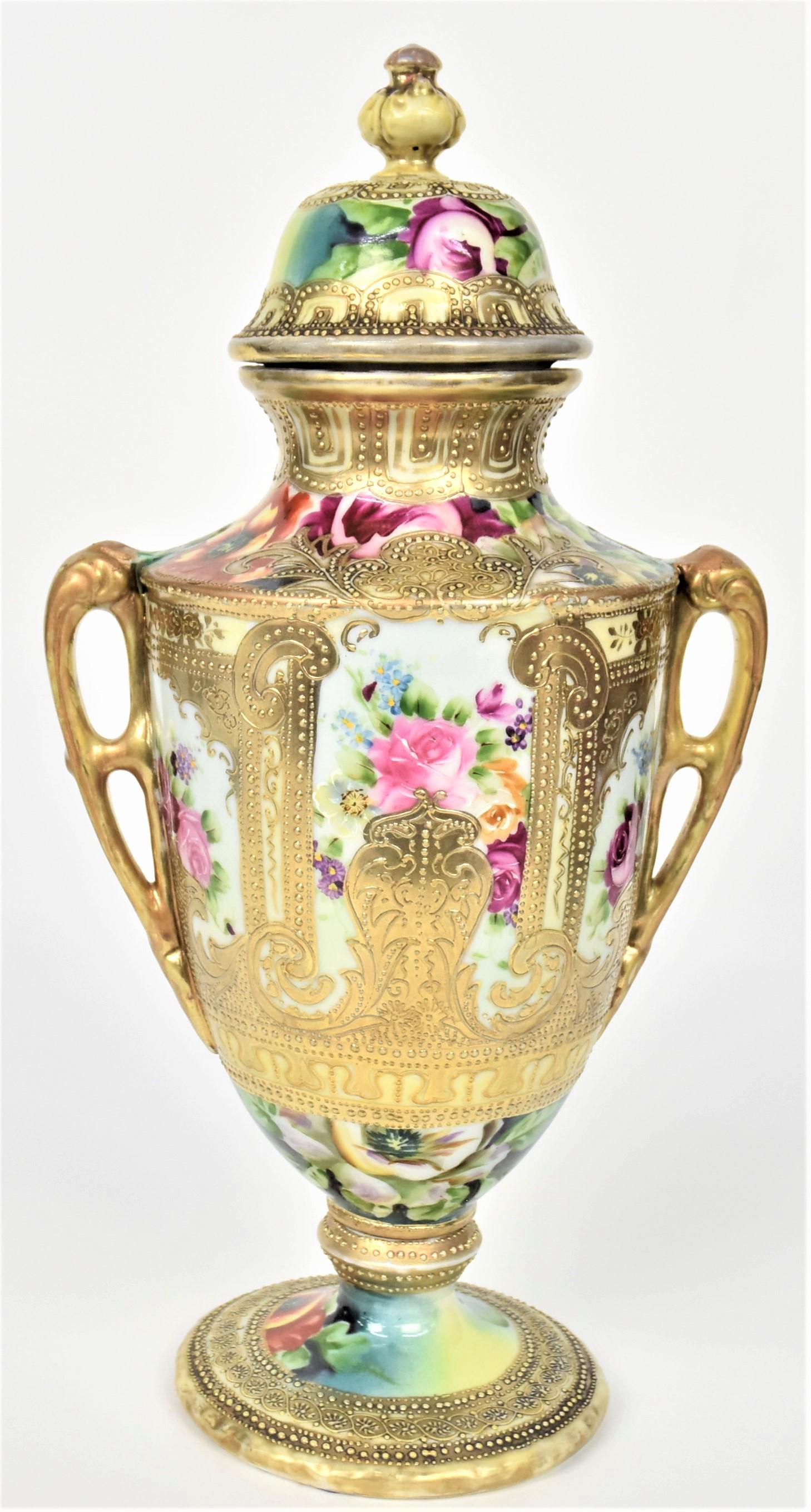 Nippon Bolted and Covered Urn with Handles.: Elaborately decorated with raised gold trim surrounding colorful flowers. Shortened and repaired both handles. Factory wishbone shaped lines below finial. 15 /4" tall. Maple leaf backstamp. Impressive
