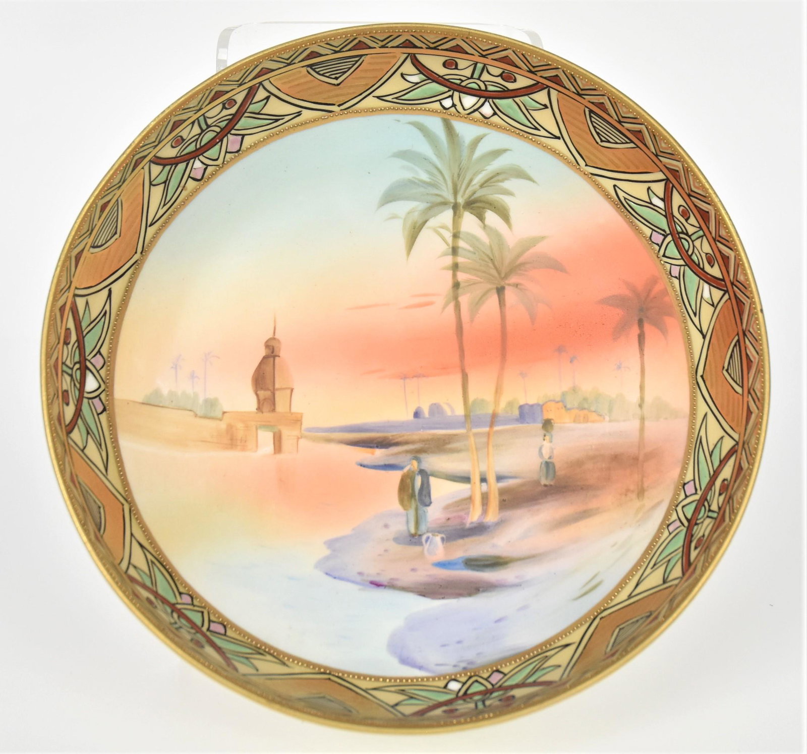 Nippon Tri-Footed Bowl: With an egyptian landscape with people. Colorful, enamel border. 3 1/8" tall, 8 1/2" diameter. M in wreath backstamp. Good condition.