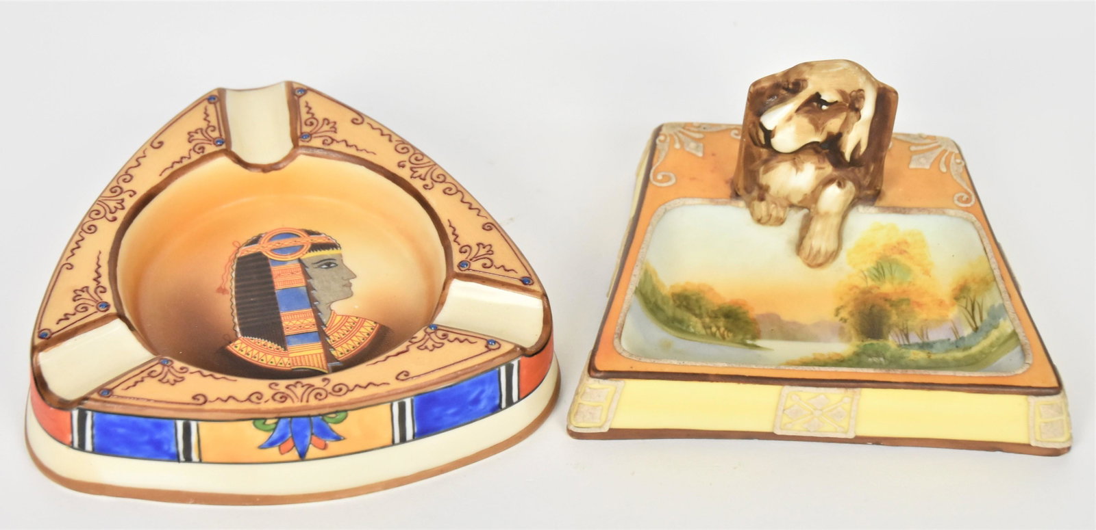 Two Unusual Nippon Ash Receivers: 1. Hound in relief match box holder with lake scene in tray. 2 1/2" tall, 4 3/4" wide 2. Egyptian portrait lead in design 1 1/4' tall, 5 1/4"diameter. Both have M in wreath backstamp.