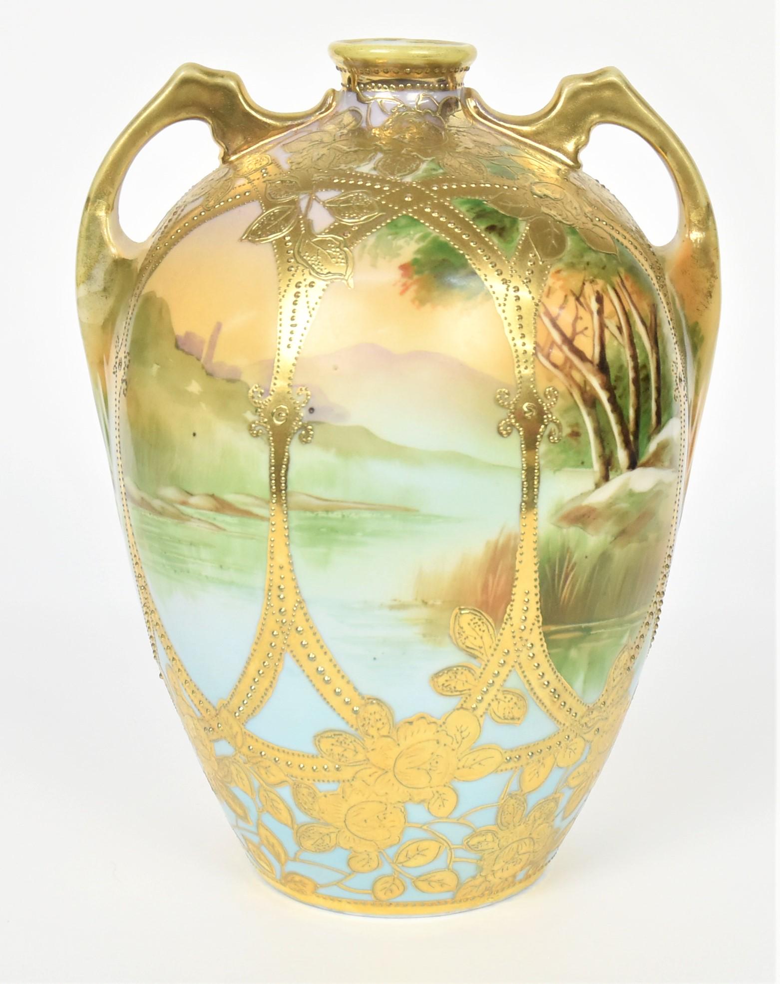 Nippon Landscape Handled Vase: With a serene lake scene caged in bright raised gold of flowers. Foliage and vines. 10" tall, 8" across. Maple Leaf backstamp. Handsome and in good condition.