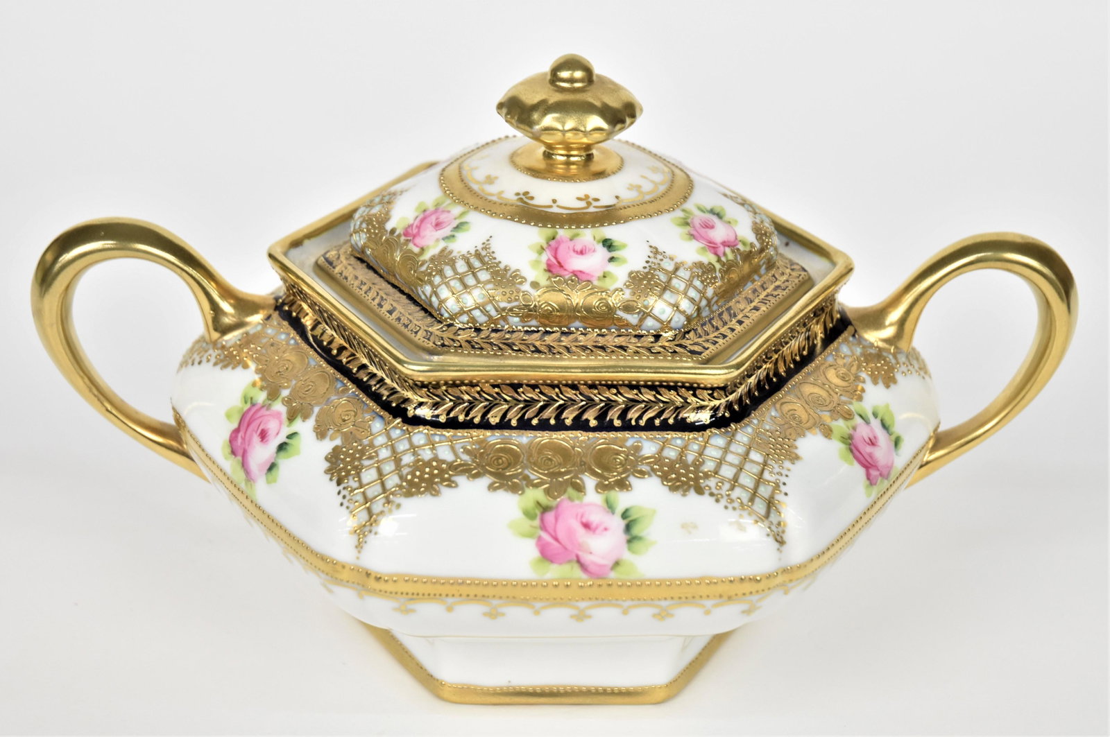 Nippon Hexagonal Covered Cracker Jar: Bright gold raised designs and a scatter of pink baby roses. RC backstamp. 6" tall, 10" across handle to handle. Showy and good condition.