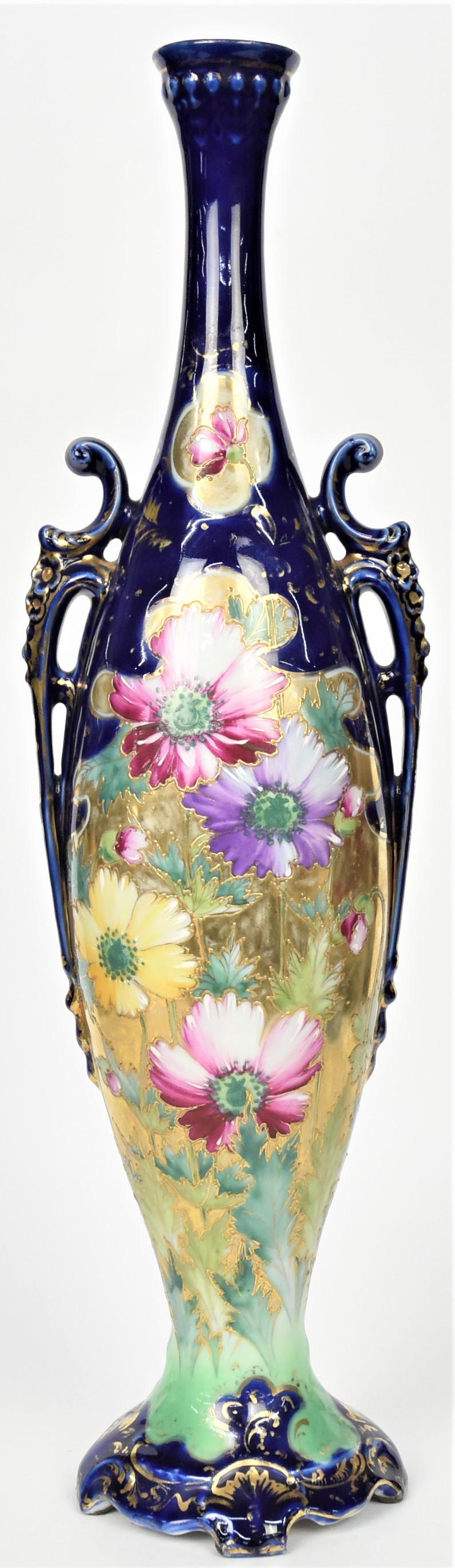 Large Nippon Cobalt Blue Scroll Handled Vase: With stalks of colorful flowers front and back against bright gold and mint green. Blow out beading at rim and on handles. Nice scrolled base. 20" tall, unmarked. Stately vessel in good condition.