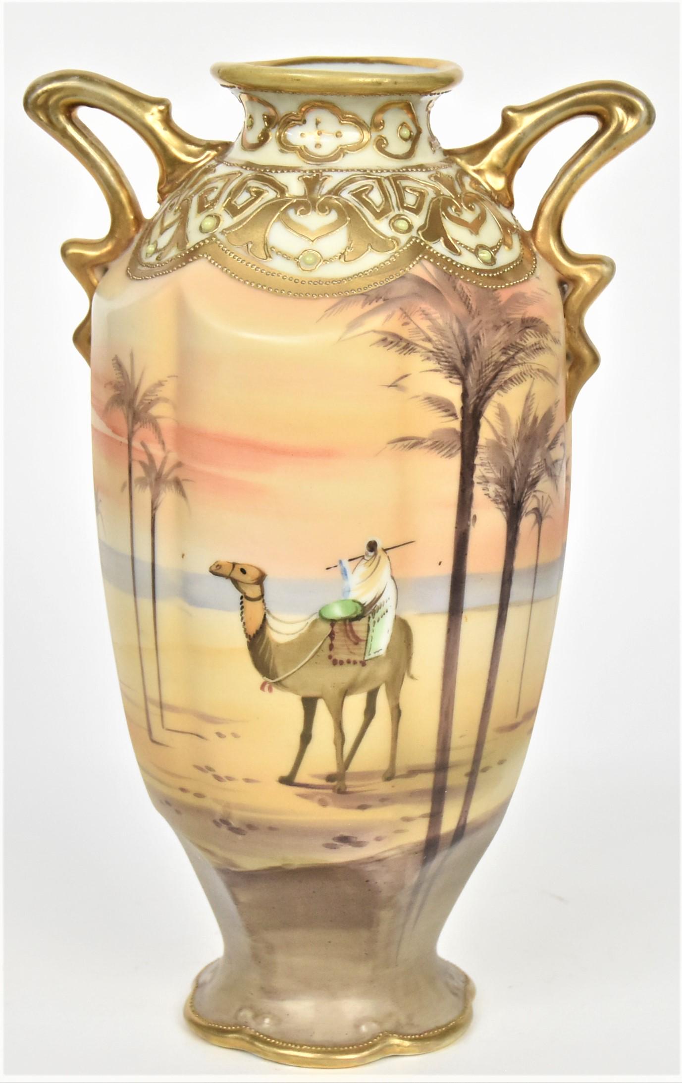 Nippon Scenic Man On Camel Handled Vase: Featuring a person riding a camel surrounded by palm trees. Raised gold trim, gold serpentine handles. 9" tall, M in wreath backstamp. Melon ribbed body. Good condition.