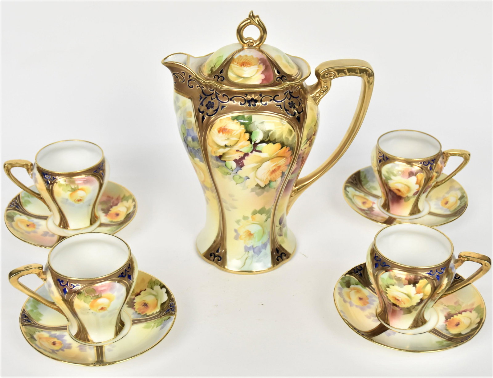 Nippon Nice Chocolate Set with Yellow Roses: Consisting a 9" covered pot plus four 3" tall cups and four 5"diameter saucers. All with yellow rose blossoms with gold relief panels. All but saucers backstamped with M in wreath logo.