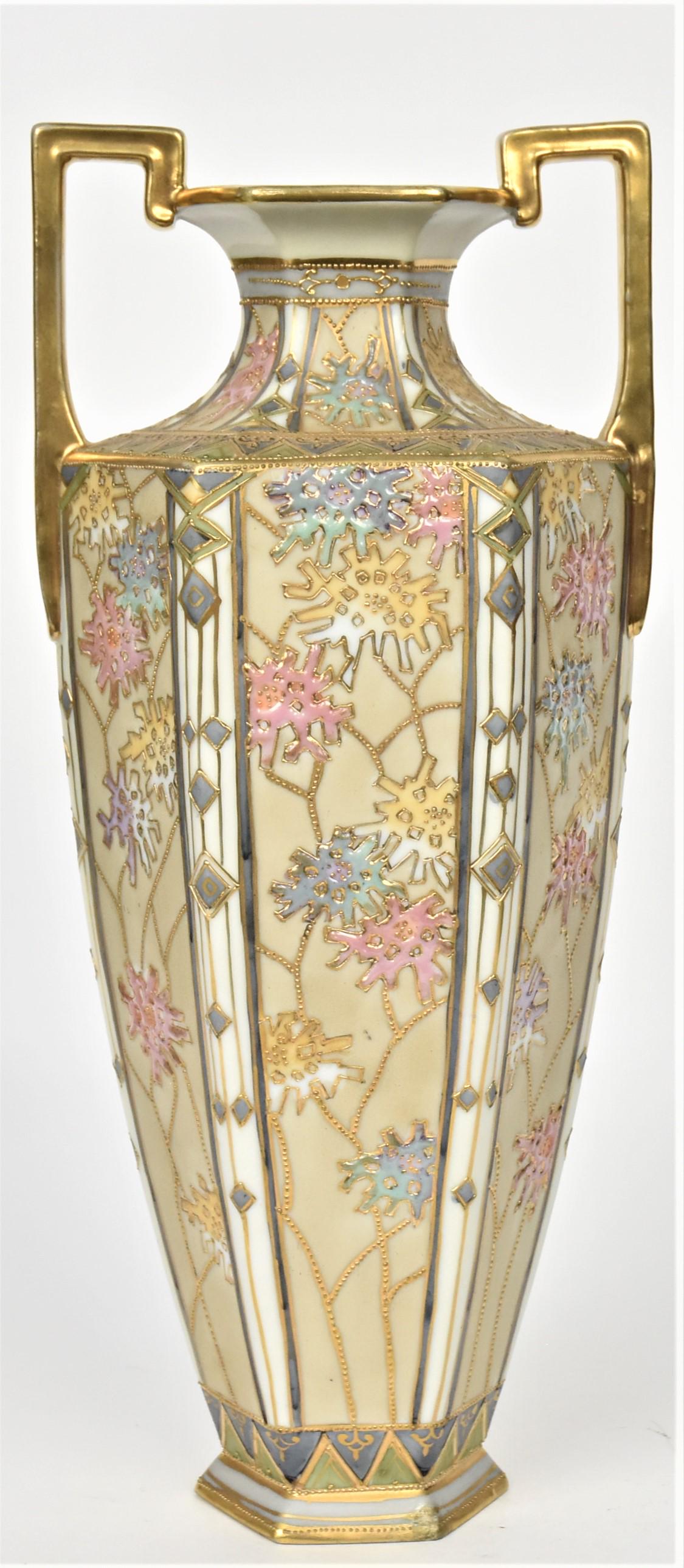 Nippon Hexagonal Vase: Each panel revealing pastel enameled blossoms on gold beaded stems. Ornate designs on shoulder and sides. 14 1/2" tall to top of gold handles, 6 1/2 across. M in wreath logo. Corner repair to base. At