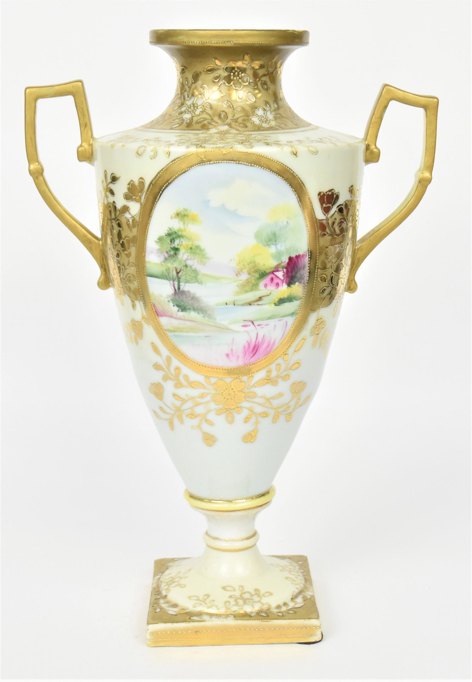 Nippon Bolted and Handled Urn: With elaborate raised gold florals connecting a scenic oval and a rose oval. 13 3/4" tall, 9 1/4" handle to handle, M in wreath logo. After factory gold applied to rim and handles, otherwise good cond