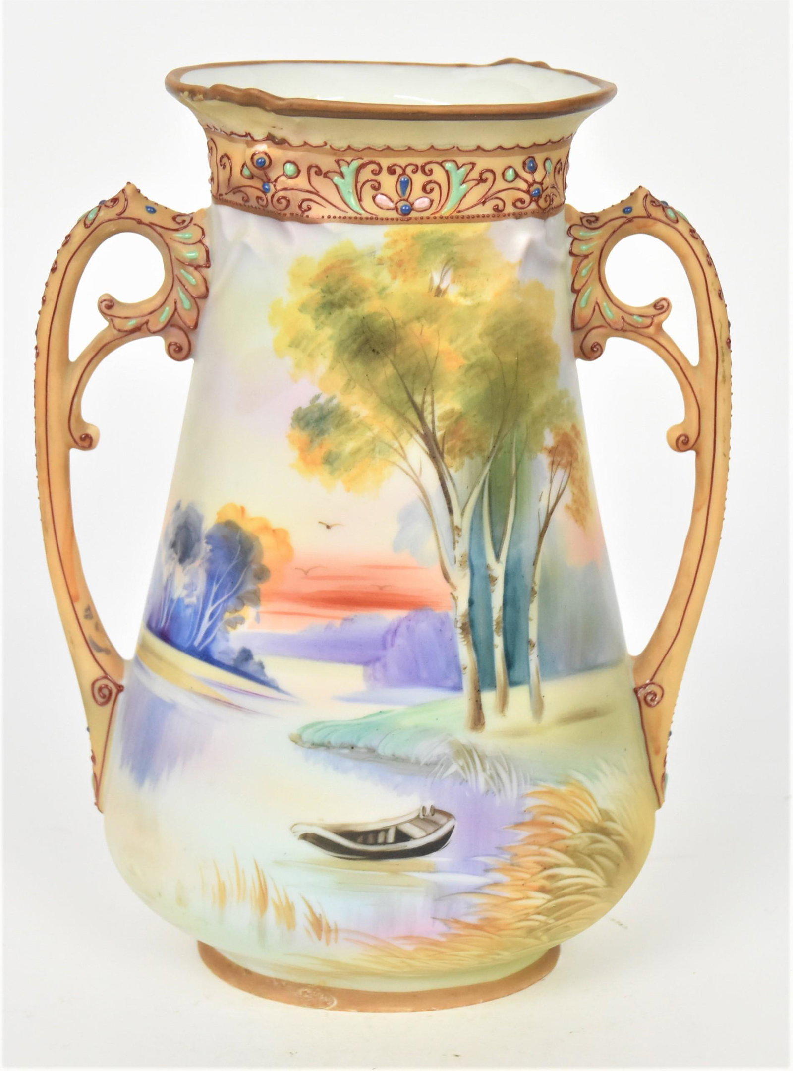 Nippon Twilight Scenic Vase: With the scrolled handles and rim accented by enamel beading and scrolls. Hidden florals in relief at rim. 9" tall, 7" handle to handle. Maple leaf backstamp. 3/8" Factory imperfection. Colorful and o