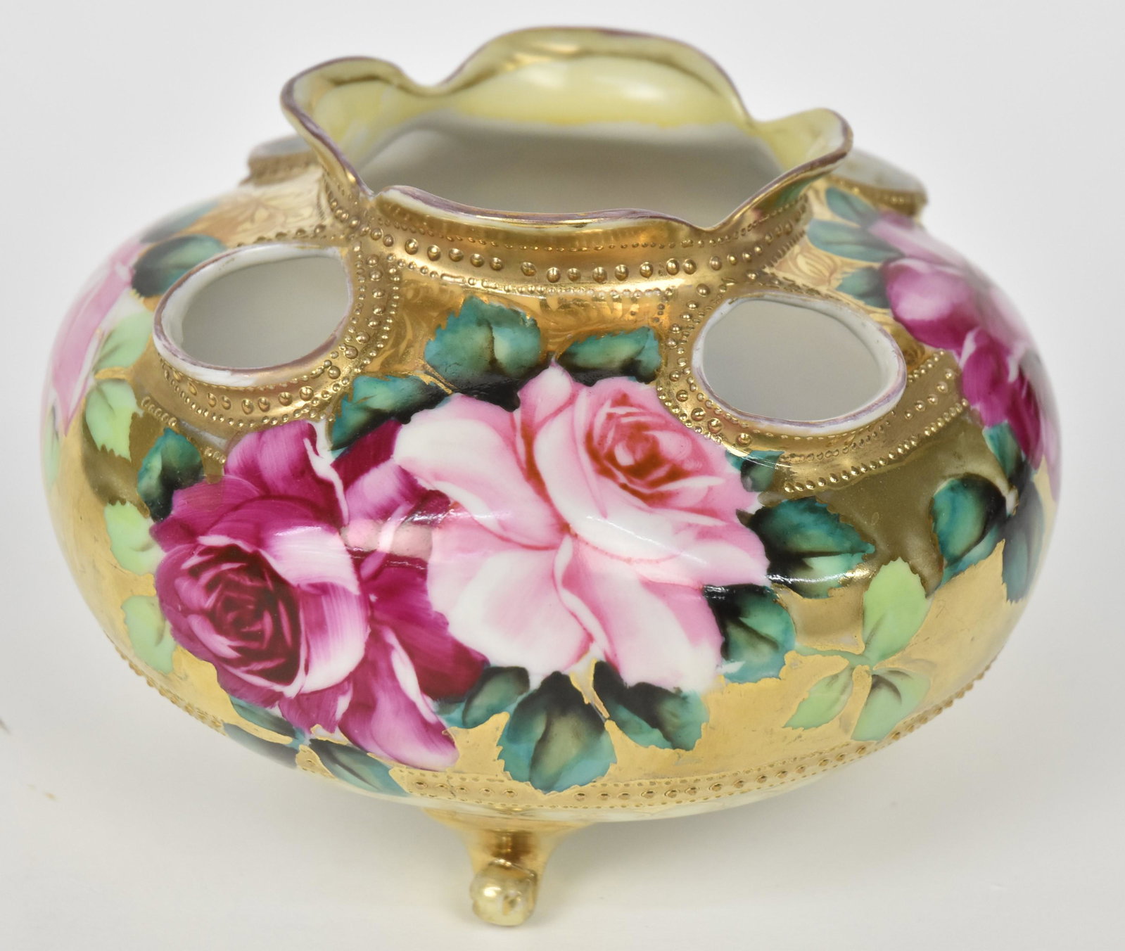 Nippon Open-Work Rose Bowl: Displaying ruby and pink roses on gold, raised gold beading. Three scrolled gold feet. One foot has repair at tip. Maple leaf logo. 4 1/4" tall . Attractive and in otherwise good condition.