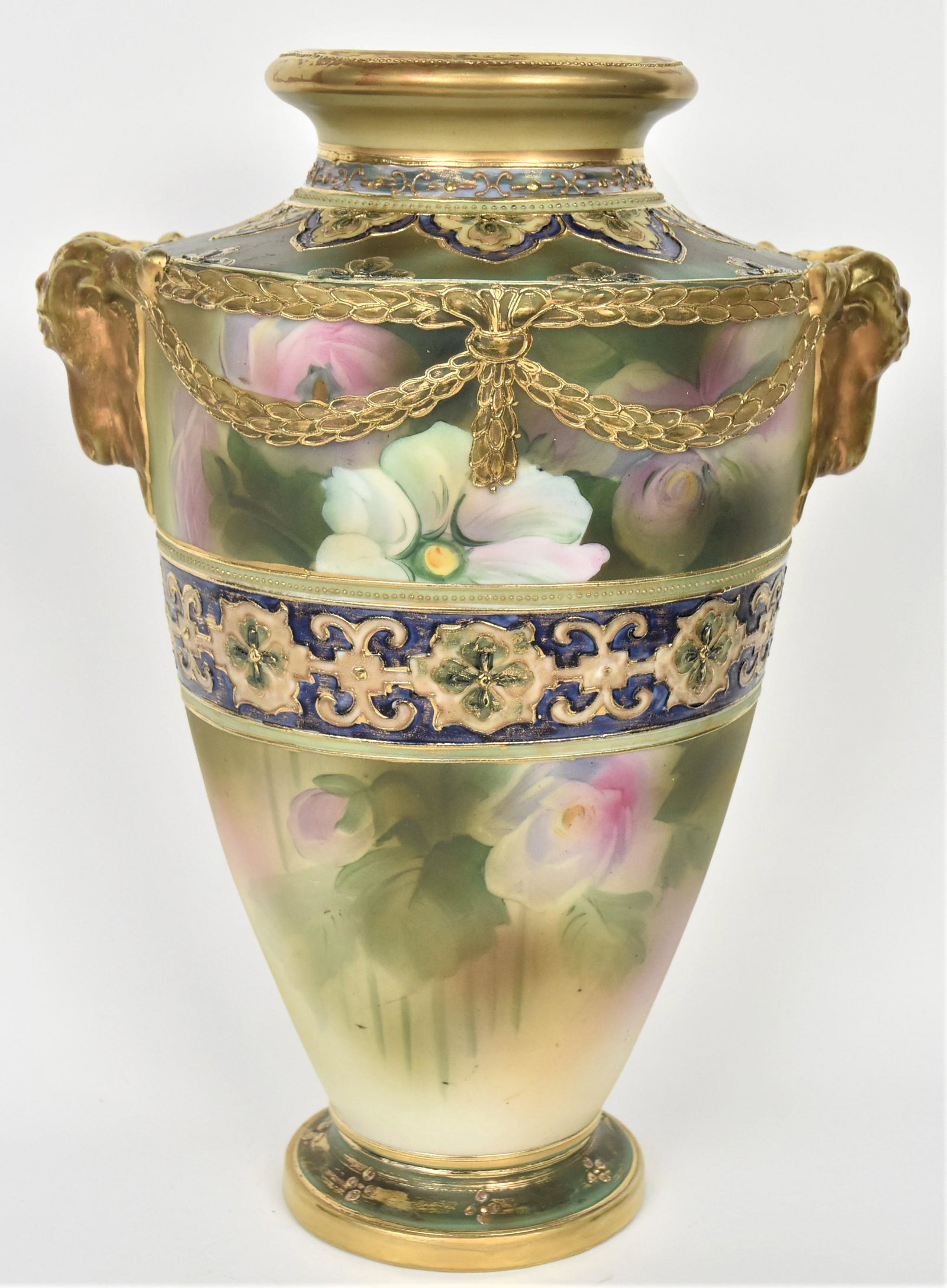 Large Nippon Rams Handled Vase: Connected by raised gold relief laurel leaf swags. Highly decorative enamel shoulder, a body band afore painted white and lavendar roses. 13" tall relief handles. After factory unfired gold applied to