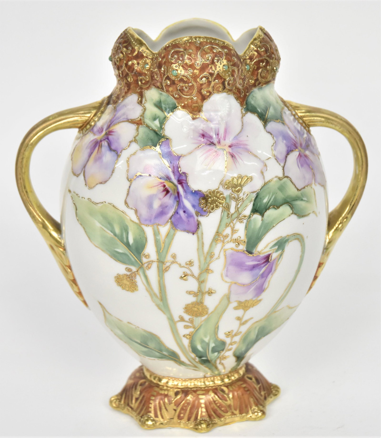 Nippon Jewel Gold Relief Vase: Featuring in relief a petal top rim with beading and acanthus leaf base. Painted lavendar pansies front and back with raised gold florals accenting. Acanthus leaf handles have after factory gold appli
