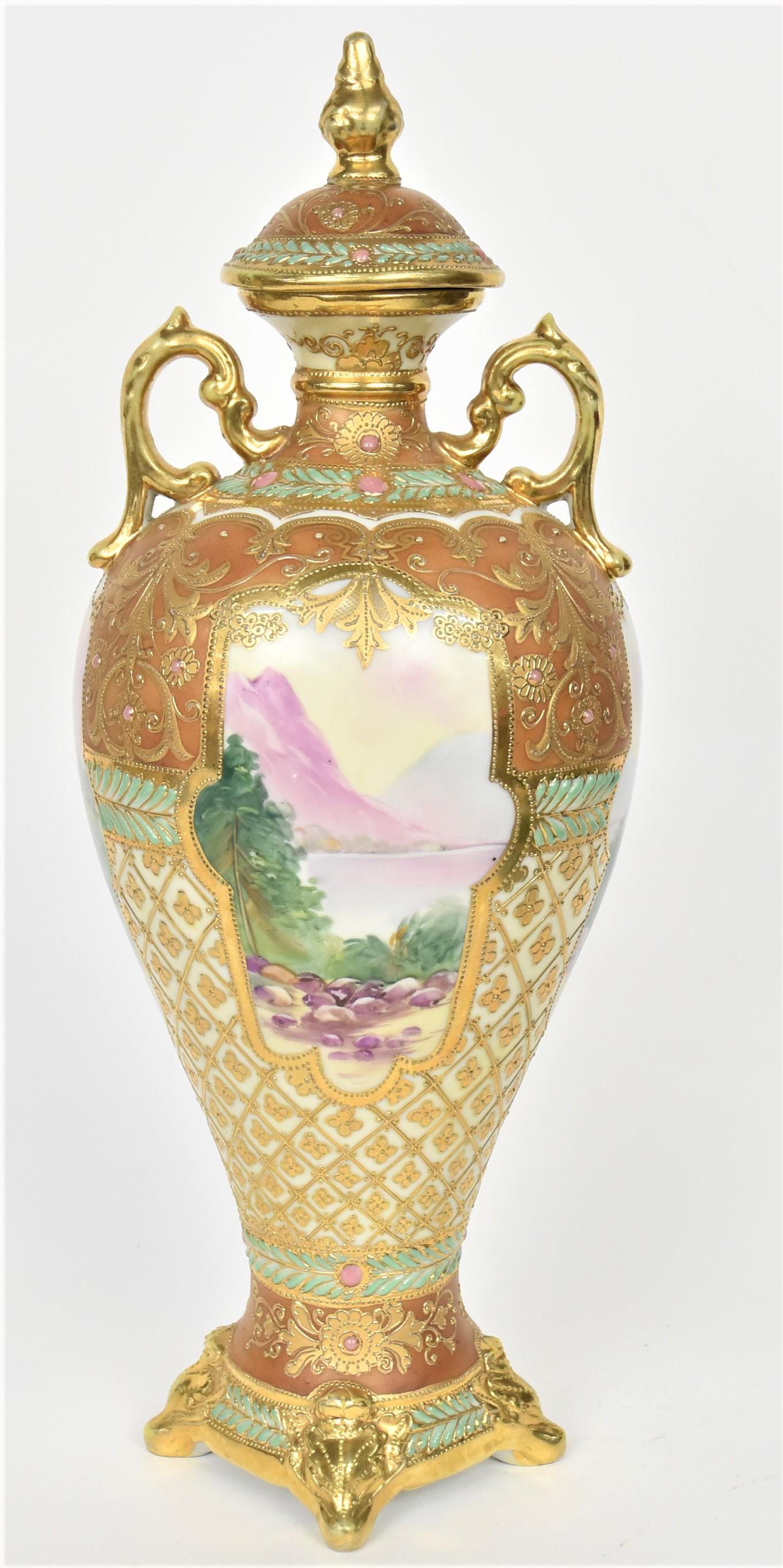 Nippon Jeweled Scenic Covered Urn: Elaborately decorated with raised gold floral nettting and foliage. Gold scroll handles, relief footed base. Four scenic panels. Maple Leaf logo, 14" tall. Cover's finial has been reattached, otherwis