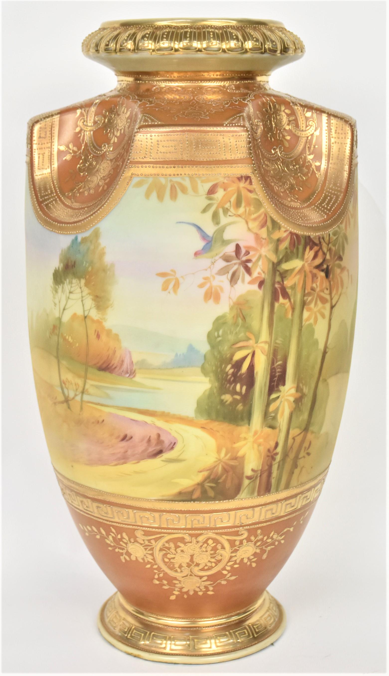 Huge 15-1/2" Nippon Landscape Vase: Displaying a continuous coastal autumn scene with frontal trees, one having a bird in the branches. Large concave rim ornate with raised gold flowers, scrolls, and Greek key designs. Relief dental rim