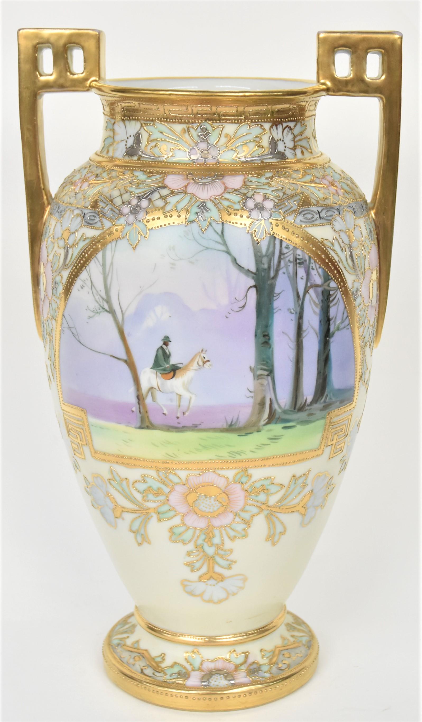 Nippon Horse and Rider Scenic Vase: Landscape on reverse, beautiful paste painted floral trim enhanced by bright raised gold, pierced gold handles. 12"tall, M in wreath logo. Delightful display. Good condition.