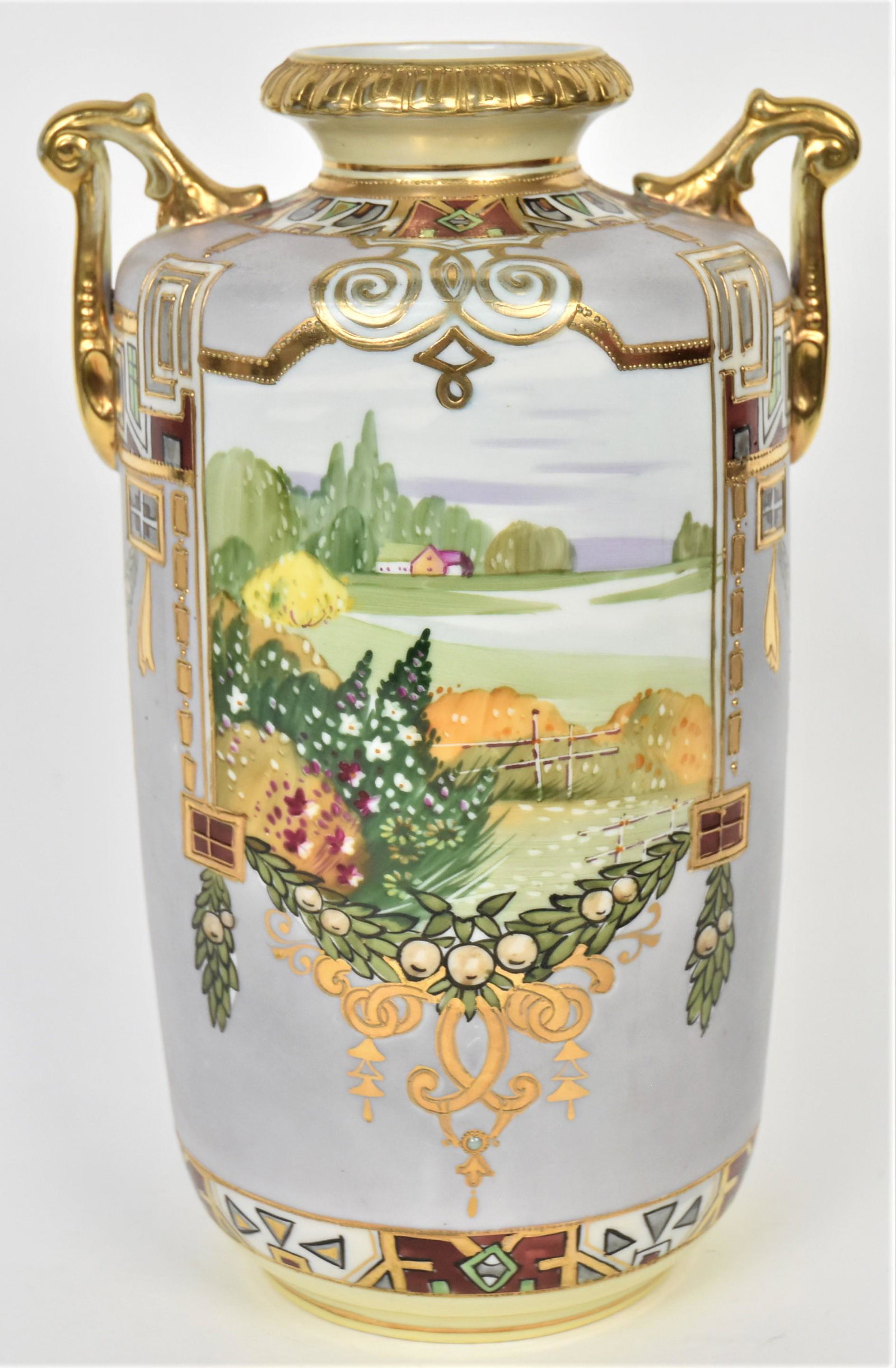 Nippon Summer Scenic Vase: Front and back landscape panels. Painted fruit and laurel leaf swags, decorative motifs highlighted by raised gold. Acanthus leaf handles, gold dental rim. 10 11/2" tall, M in wreath logo. Impressive 