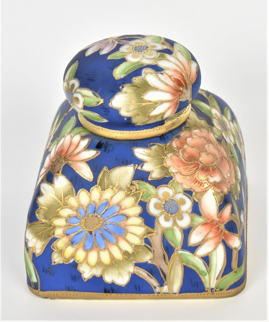 Nippon Stylized Floral Inkwell: Delightful multi-colored against a cobalt backdrop. 4" tall, M in wreath logo. Features a porcelain insert, repaired and missing pieces. Chip 3/8" on containers rim, concealed by the cover. Beautiful 