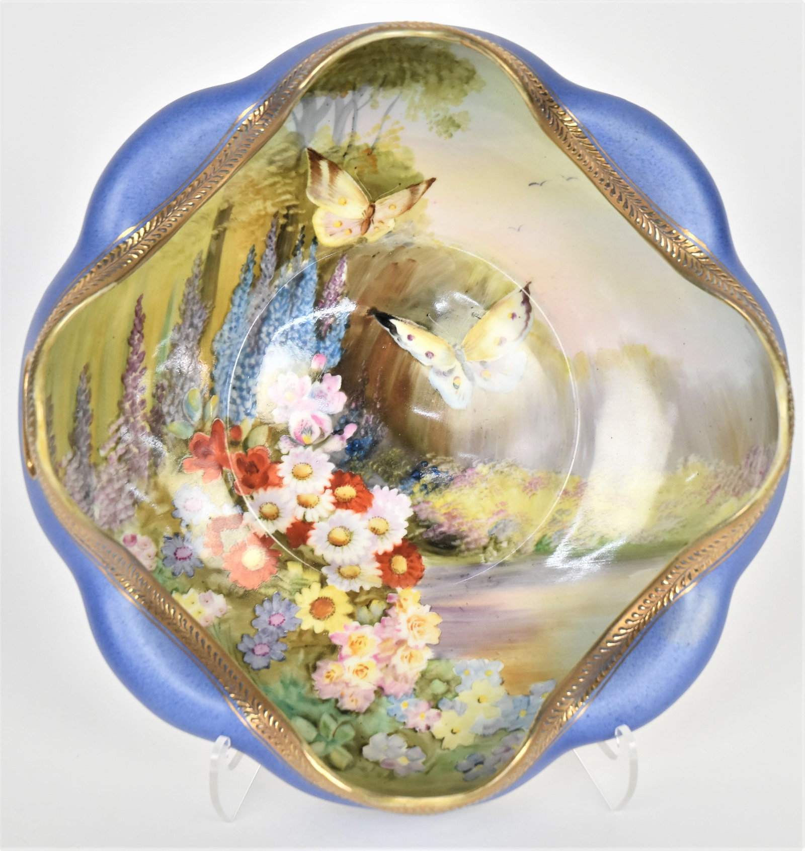 Nippon Scenic Bowl: Featuring a old fashion garden bountiful with an assortment of brightly colored flowers, visited by two butterflies. Deep fold in blue rim decorative with raised gold ferns and cut out handles. 4"tall