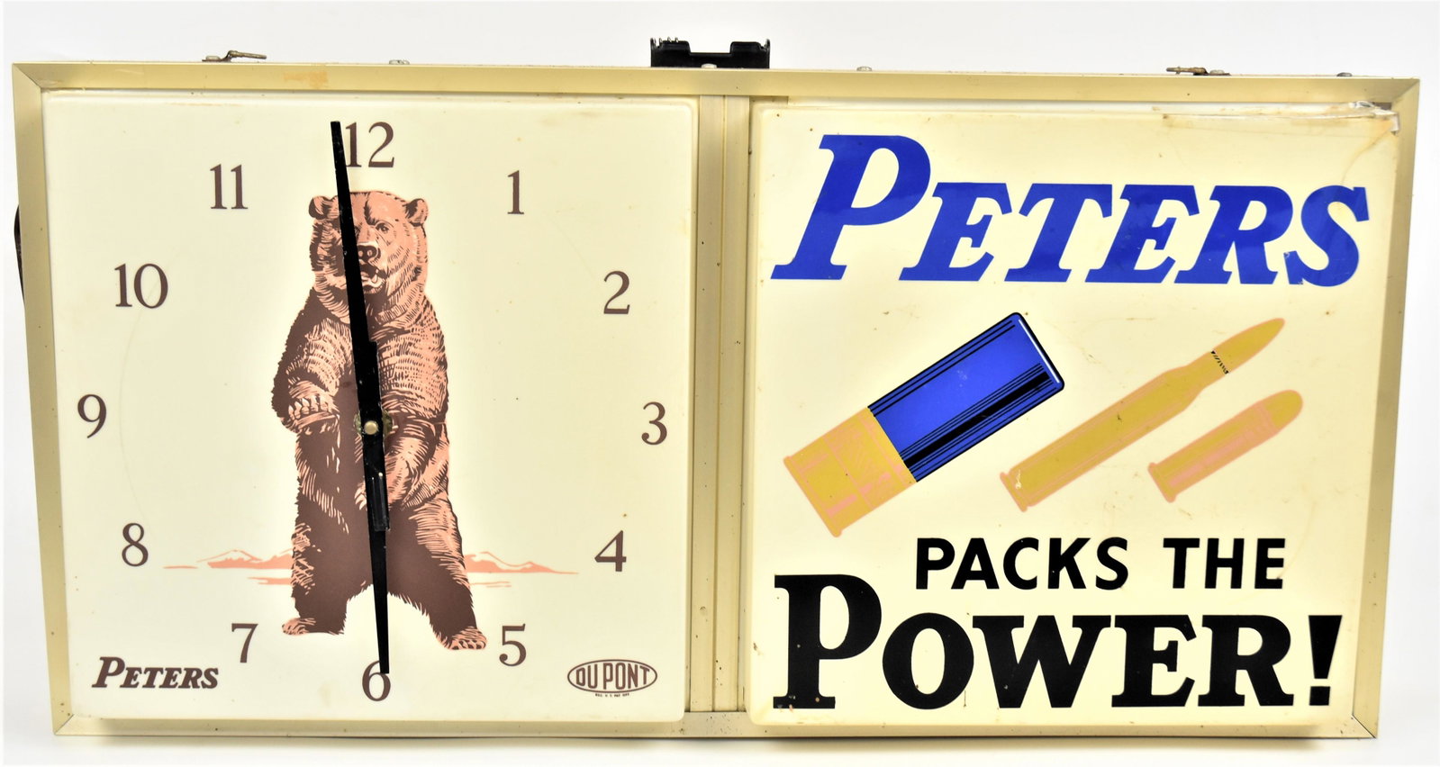 Lighted Peters Cartridge Clock: Clock dial on left with Arabic numerals and illustrated with standing Alaskan Brown Bear with Peters lower left & Du Pont lower right; right side with illustration of two Peters Cartridges and one sho