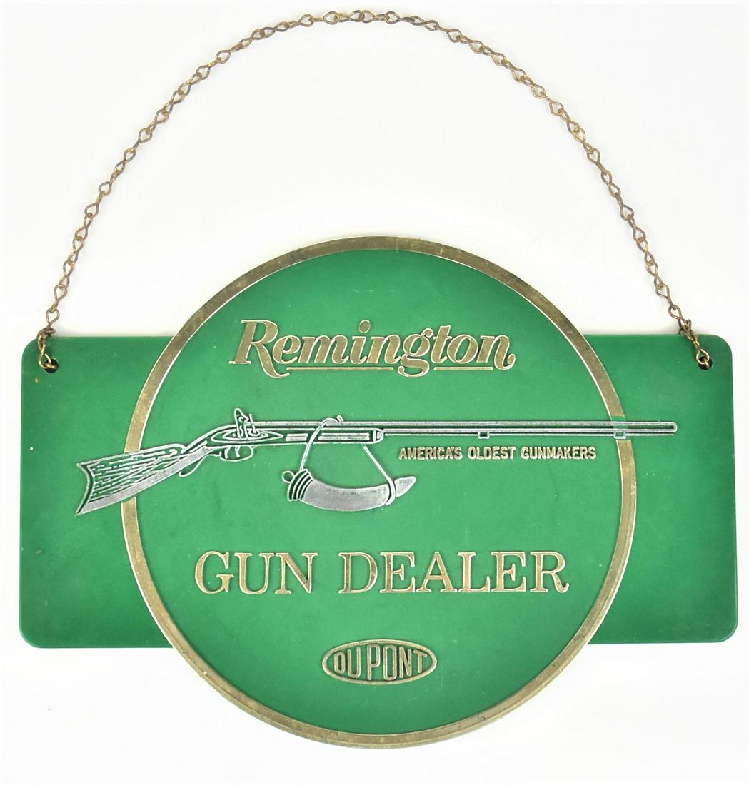 Remington Door Hanger Sign: Molded green plastic with relief flintlock rifle with powder horn with Remington above and Gun Dealer Du Pont below with original brass chain hanger, 11 1/2 x 8 1/4" high. Condition VG+.