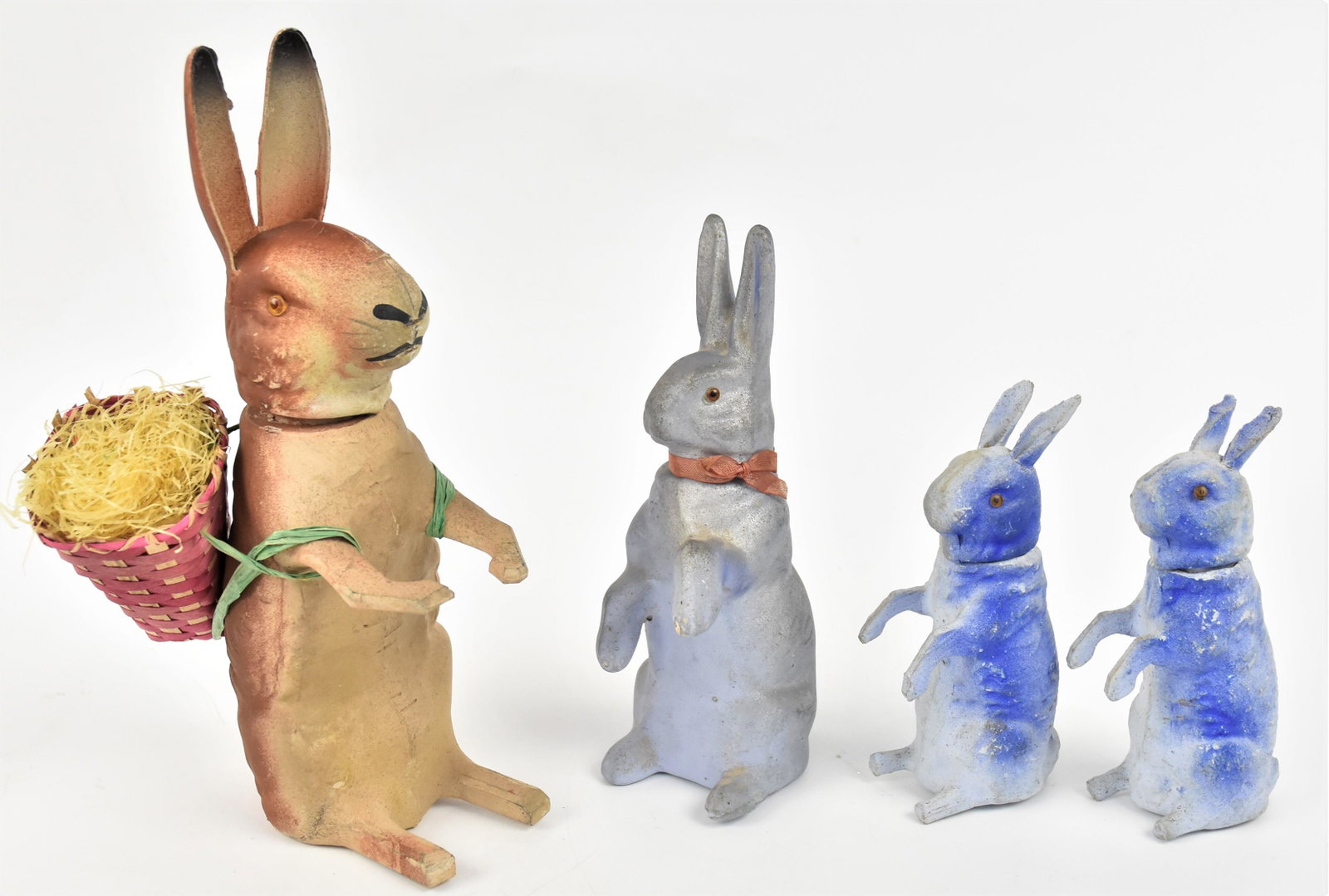 Easter Candy Containers: Lot of four all papier-mache rabbits standing on hind legs, all with glass eyes, three smaller marked Germany, all polychrome painted, 5 3/4, 7 7/8 & 10 1/2" high. Condition minor wear VG.
