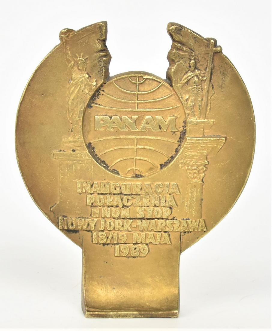 Pan Am Bronze Commemerative Paper weight: Cast Pan Am globe symbol with Pan Am, flanked by Statue of Liberty on left and Statue in Warsaw Old Town Square with inscription reading Inauguracia Polaczenia Non Stop Nowy Jork-Warszawa 18/19 Maja 1