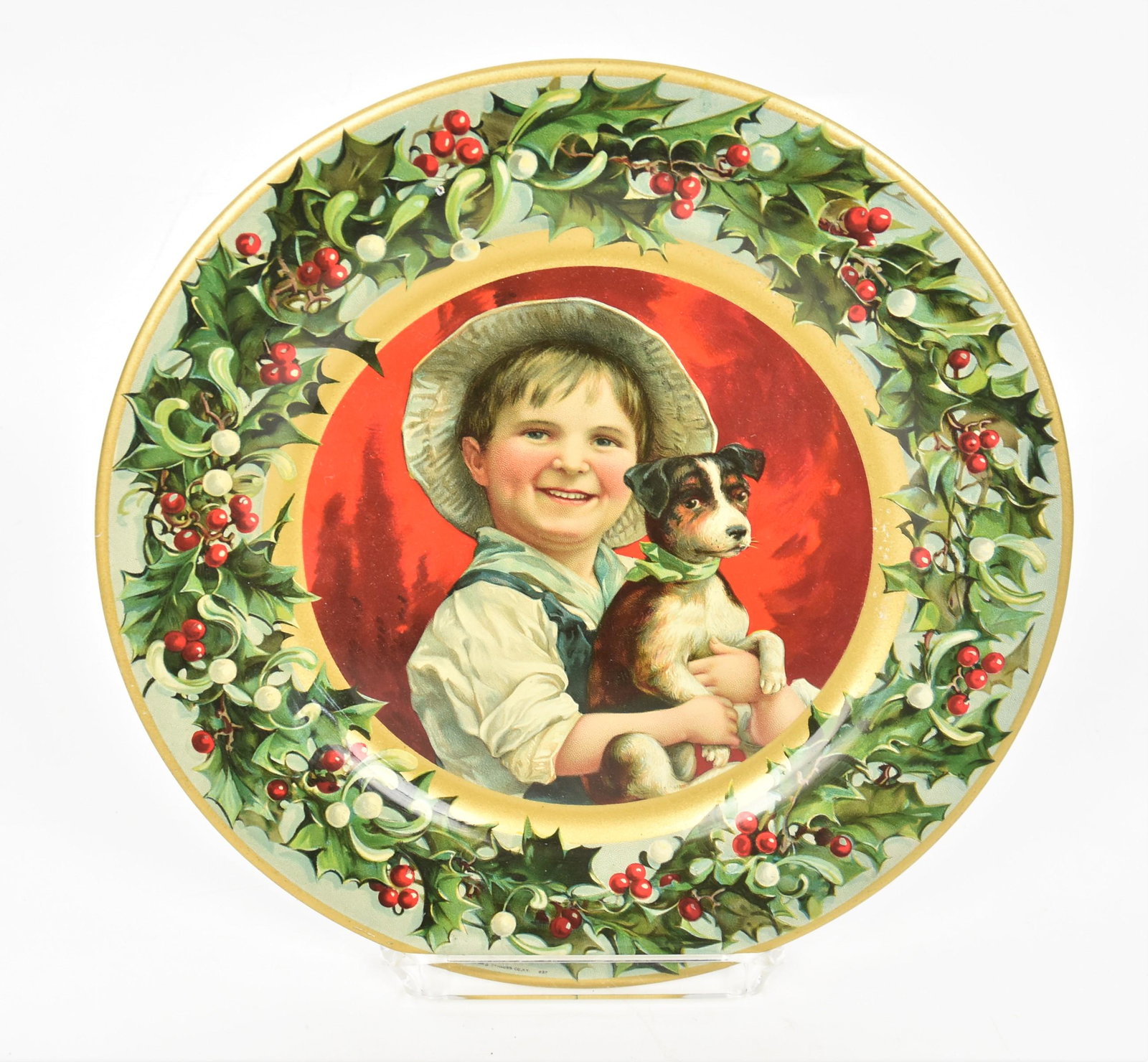 Chromolithographed Christmas Gier Wine Co. Tin Plate: Marked Kaufman & Strauss Co. N.Y. 997, center with young boy in hat holdinh puppy with green bow at neck, holly wreath surround, 9 1/2" diameter. Condition paint 97%.