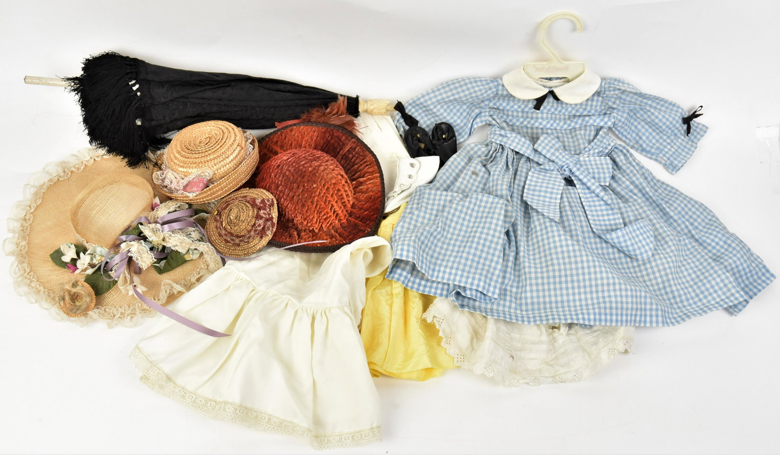 Early Doll Clothing: Lot includes five hats; pls pair of leatherette shoes; plus umbrella with whale bone carved finial, 20" high; plus pair of doll gloves; and on dress & three skirts. Condition All VG.