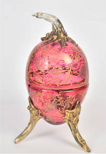 Ornate Cranberry Egg Form Covered Container: Enamel floral design. Unusual gold branch feet & finial. 10" H x 4 3/4" W, wear of gold. Good condition.