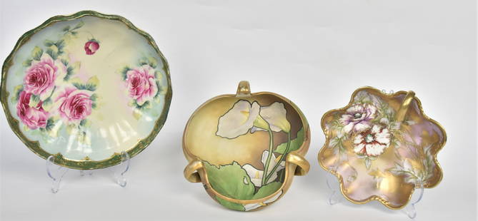 Three Nippon Hand Painted Pieces: A tri-form handled bowl, 3" x 8"D with large lilies & foliage, a handled nappie, 2 1/2" x 7/12dia with poppies and gold highlighting, a center bowl with pink rose boquet, 3" x 10" dia. Small repair