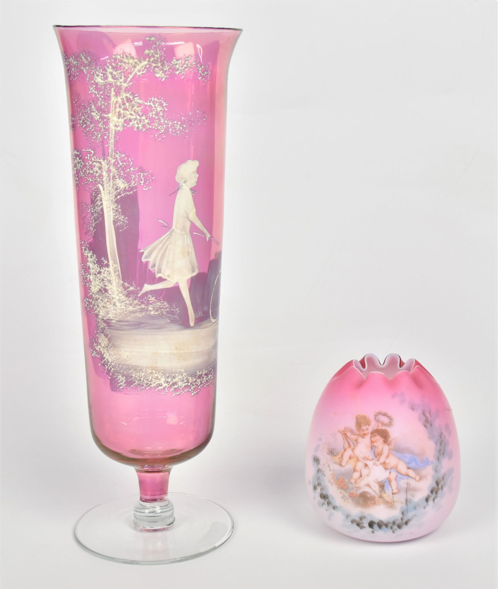 Peachblow Art Glass & Mary Gregory Vase: Lot of two including a tall cranberry Mary Gregory mantle vase with a young lady & a hoop decoration 11 3/4" high; and a satin peachblow rose bowl with cupids and doves 4" high. Condition both VG.