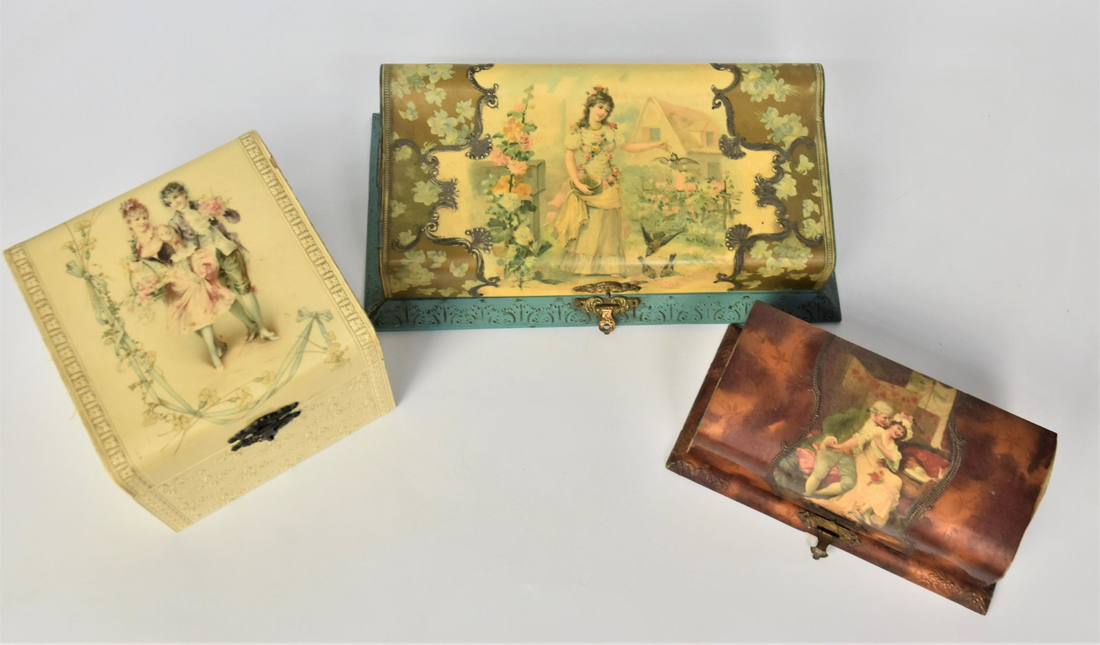 Three Edwardian Celluloid Boxes: All cira 1900-1910 with chromolthographed portraits of couples and young lady in 18th century or Victorian dress, including a jewlery box likely for necklace with gee lid, brass clasp and satin liner,